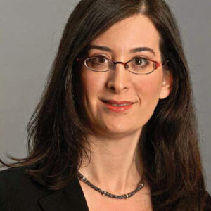 wpa_people_page_nancy_rothbard A headshot of a person with long dark hair, wearing glasses, a black blazer, and a necklace, set against a neutral background.
