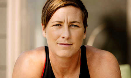 Headshot of a person with short hair, wearing a sleeveless top, looking directly at the camera with a neutral expression.