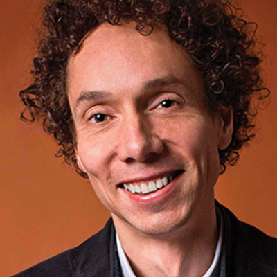 Headshot of a person with curly hair, smiling, against a warm brown background.