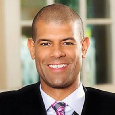 A person in a suit and tie smiling in a headshot.