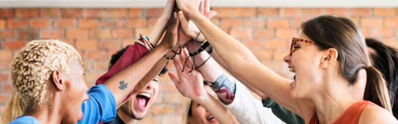 A group of people celebrating with a high-five, expressing teamwork and joy.